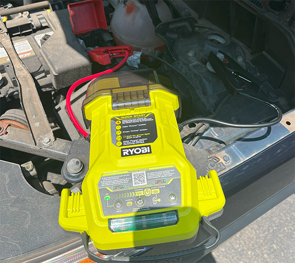 Ryobi 18V Cordless Battery Jumper in Car Engine Bay Connected to Grounding Lug